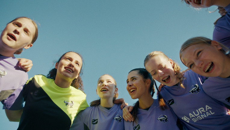 Kapitänin Büsra (Ronahi Gul, 2. v. l.) schwört ihr Team vom FC Virtus 04, darunter Marie (Lotta Vetterlein, r. neben Büsra) und Neuzugang Raya (Helena Yousefi, r. neben Marie), mit dem traditionellen Schlachtruf auf die kommende Saison ein. Teamgeist und Zusammenhalt stehen dabei an erster Stelle.
ZDF/Lilly Merck
