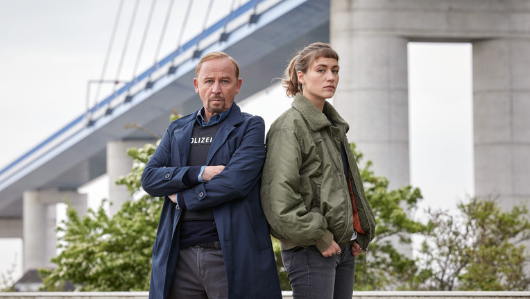 Ab sofort gehen sie gemeinsam auf Verbrechersuche: Karl Hidde (Alexander Held) und die neue Kommissarin Jule Zabek (Sophie Pfennigstorf)- hier vor der Rügenbrücke. / Nutzung des Bildes nur in Verbindung mit der Sendung inkl. Social Media 
//  ZDF/Sandra Hoever
