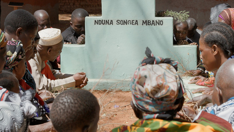 Die Protagonisten John Mbano, Aidan Mbano und ihre Familie gedenken dem ermordeten Songea Mbano an dessen Grab.